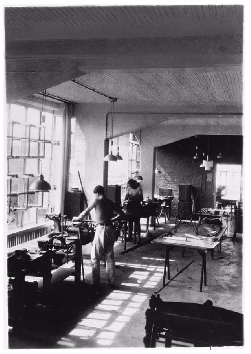 Dessau workshop glass curtain wall photograph - Metal workshop, Bauhaus Dessau, 1927-29. The workshop wing of the building was acclaimed for its innovative use of a structural concrete frame, which freed the exterior walls from any load-bearing function and allowed for the spectacular glass curtain wall. Frequently photographed from the exterior, this shot shows a less familiar view from the interior, where the massive supportive pillars are visible within the airy light-filled workspace.