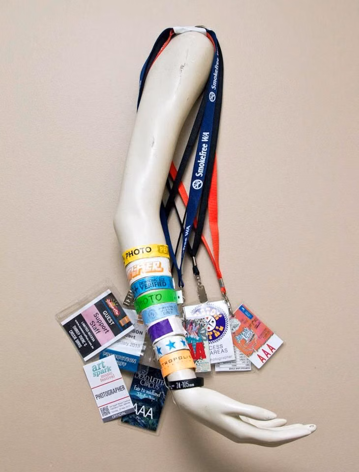 used concert wristbands collection photograph - Perry DeGennaro Photography came up with the idea of mounting a mannequin arm to his wall as a display for the media passes and wristbands given out at the music concerts he photographs.