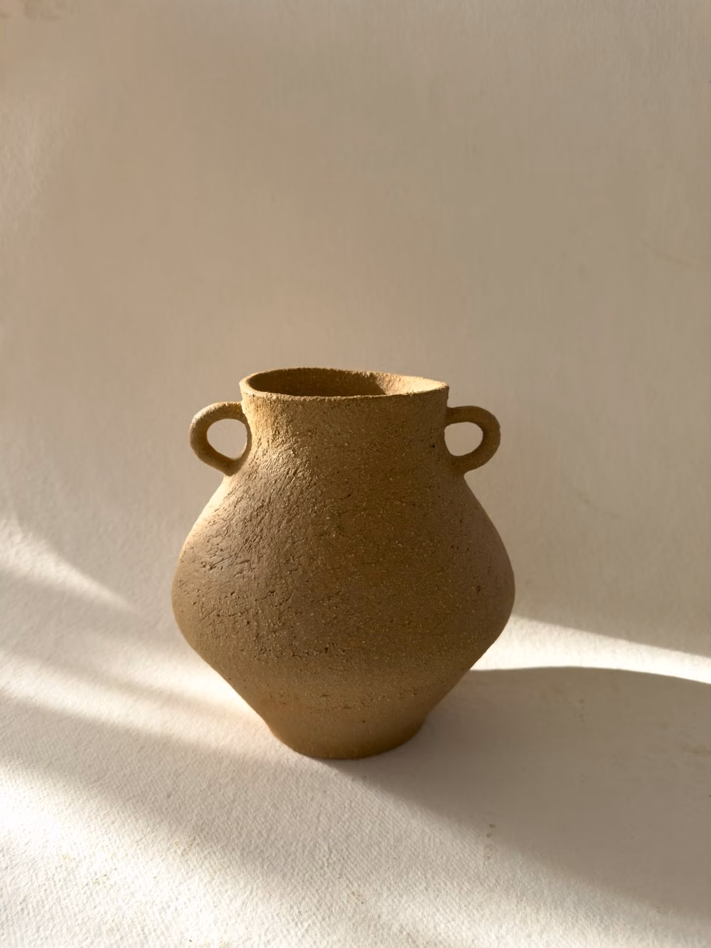 single unglazed ceramic vessel white background photograph - Introducing Dione, inspired by the ancient goddess. This vessel holds a distinct form and irregular mouth, giving it a unique, irreplaceable character.
Hand- coiled from stoneware clay with coarse grog that creates a rough and organic texture on the surface. Left unglazed on the outside to show the natural beauty of the clay, and glazed on the inside for functional use.
#pottery #ceramics #ceramicart #ceramicvessel #ceramicvessels #potteryvases