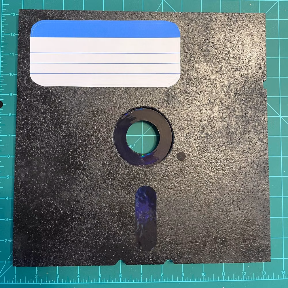 3.5 inch floppy disk close up photograph - Relive the simpler times with this 12x12 inch cork pinboard in the style of a 5.25" floppy disk! Perfect for a collection of retro computer or video game enamel pins. This would make an excellent gift for a gamer who remembers starting their games by typing LOAD "*",8,1, or excitedly browsed the shareware games at the 3 for $5 booths at the computer fair. The label is not attached, so you can leave it off or use your own. Mounting strips are included. Pins are NOT included - assemble your own personal collection!