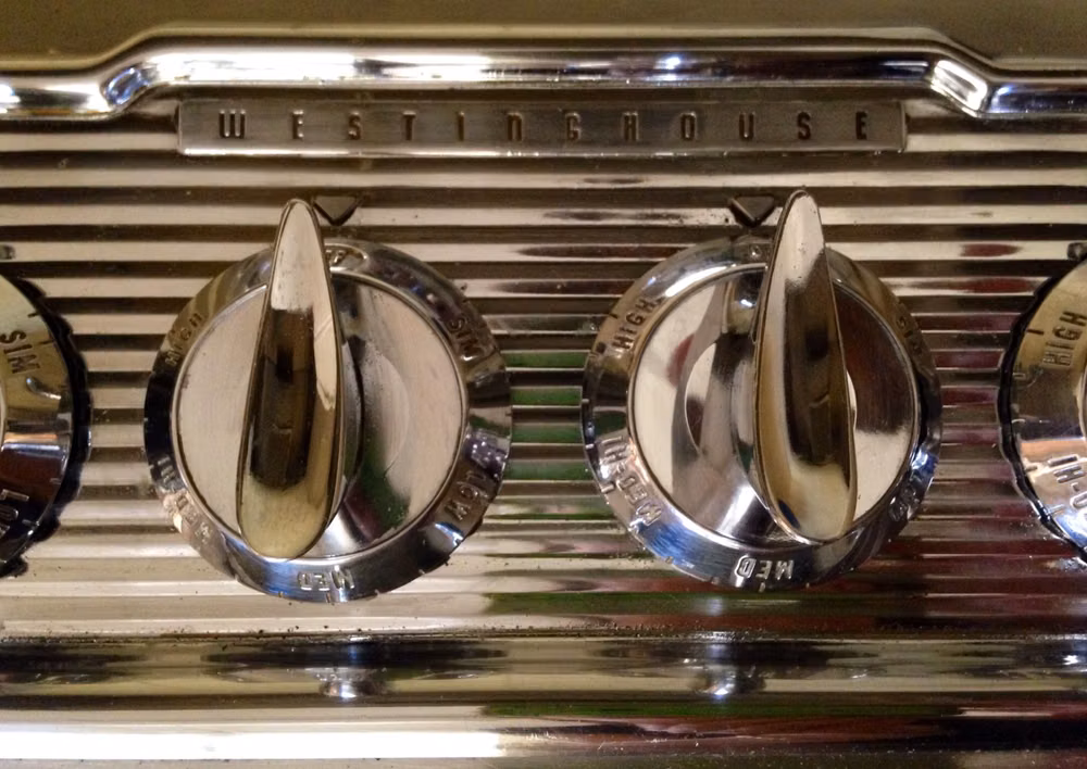 1930s chrome kitchen appliance photograph - Knobs on my stove top. The chrome detail looks like it belongs on a classic car. Late 1950's.