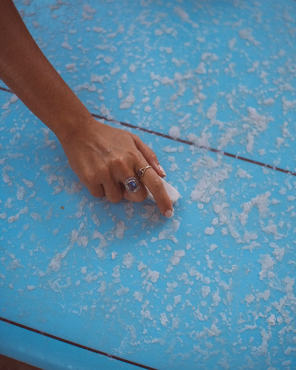 surfer rubbing wax bar on surfboard deck close up photograph - Wax on, worries off. Board-ready, island life fully loaded. 🏄♀️