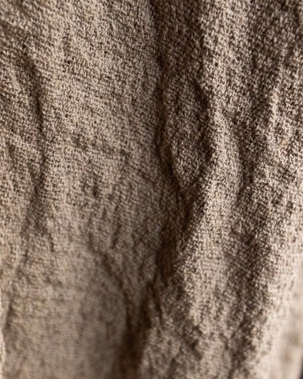 worn natural linen wrinkles macro photograph - This incredibly beautiful material actually brought us some adventures. It's woven in raw linen yarn, thick and unpolished, and we expected after wash it gives much shrinkage. We love to use this special kind of imperfection, so we boiled fabric to highlight the little wrinkles and add more, then boiled pants after sewing (it was not an easy task for my mum to count length correctly with all the double shrinkage and alive structure, so we ended up testing on a few sample pairs). DREAMERS pa...