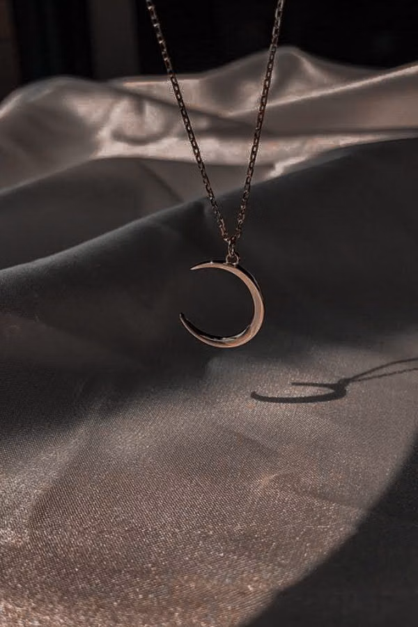 silver crescent moon jewelry close up photograph -